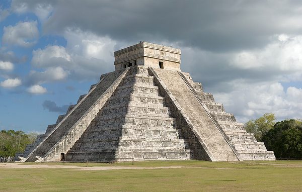 A stepped stone pyramid with stairways on each face and a square temple building standing on its flat summit