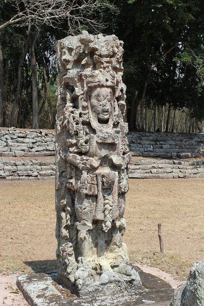 A tall carved stone pillar showing a human figure in an elaborate headdress