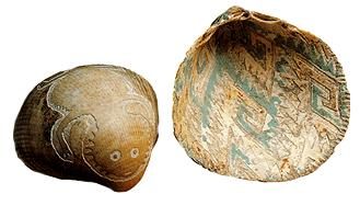 Two marine shells carved with designs &mdash; one a lizard-like animal, one a geometric pattern