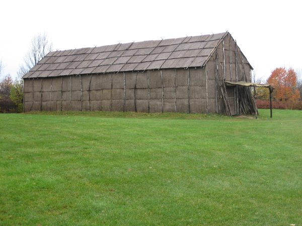 A long bark-covered longhouse standing in a field