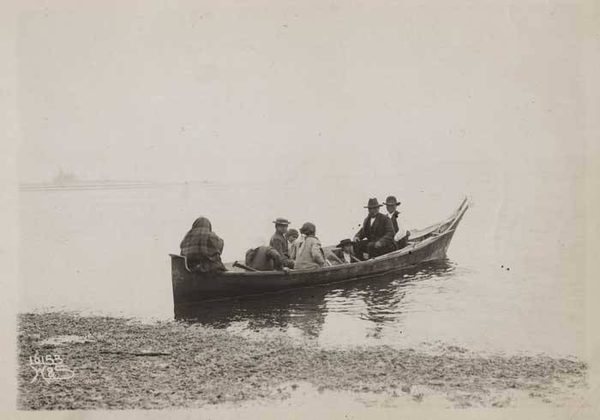 A family in a dugout canoe under way on open water