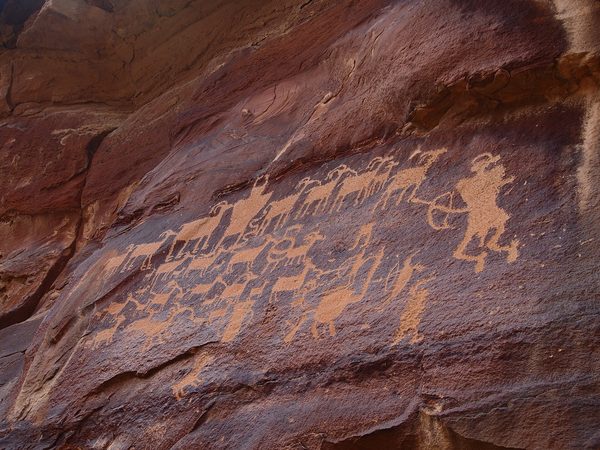 Figures of animals and a hunter pecked into a red rock face