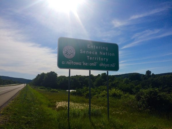 A green highway sign reading Entering Seneca Nation Territory, with Seneca-language text below